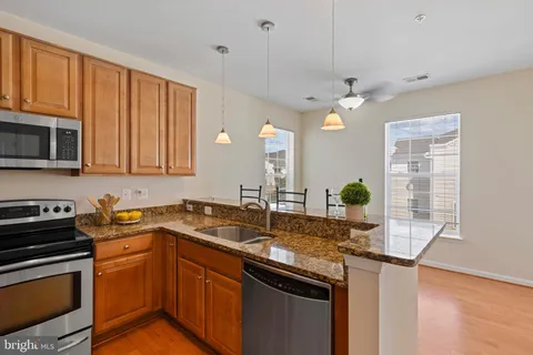 a kitchen with stainless steel appliances granite countertop a sink a stove cabinets and wooden floor