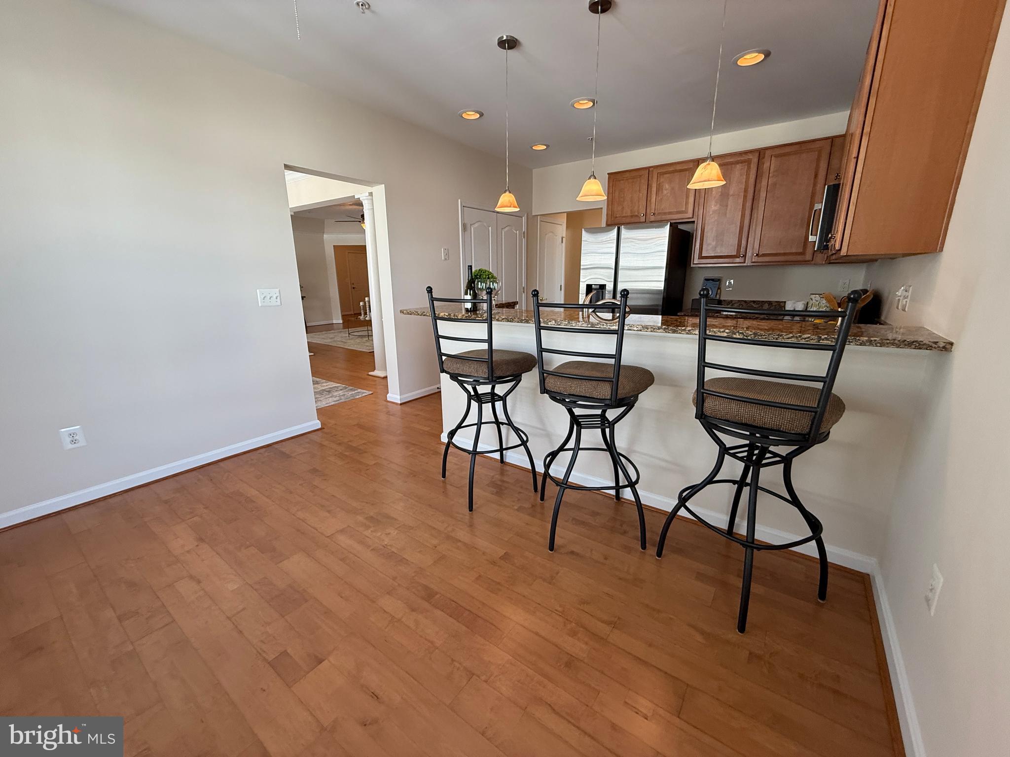 7315 Brookview Road, Unit 407 Elkridge, MD 21075 - Photo 15 of 33 a kitchen with stainless steel appliances kitchen island granite countertop a stove a sink and a refrigerator with wooden floor
