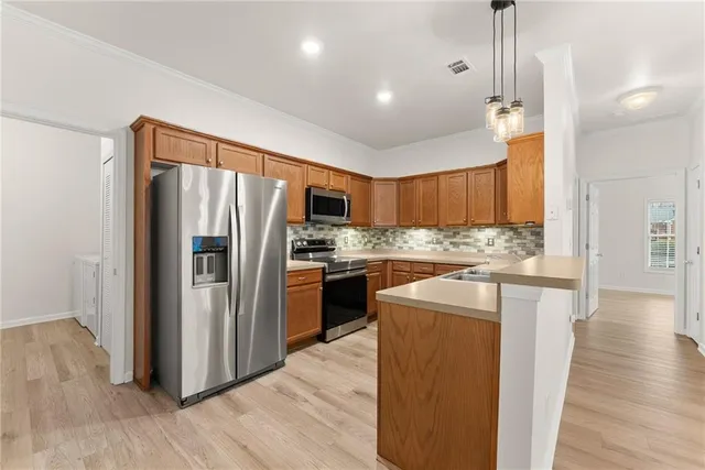a kitchen with stainless steel appliances granite countertop a refrigerator a sink a stove and a wooden floors