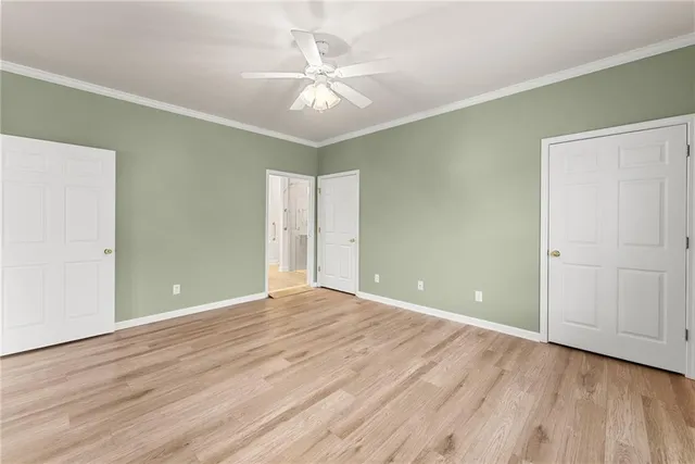 an empty room with wooden floor and fan