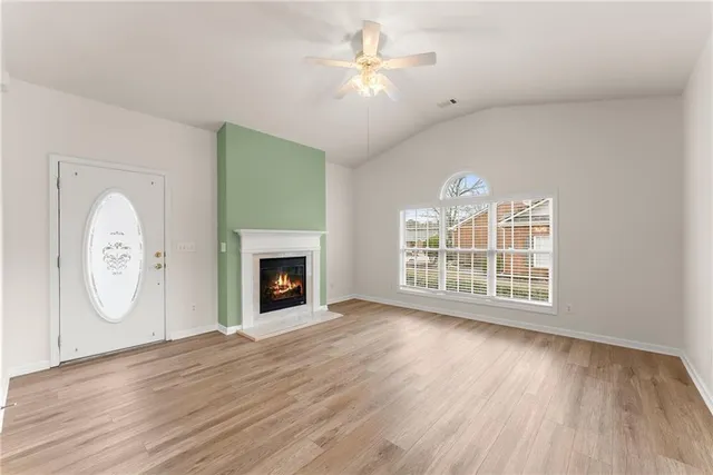 an empty room with windows fireplace and a ceiling fan