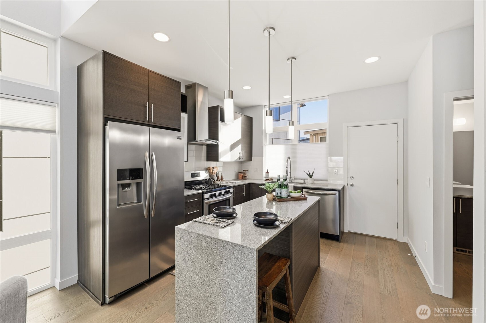 3010 63rd Avenue Southwest, Unit A Seattle, WA 98116 - Photo 14 of 38 a kitchen with stainless steel appliances a refrigerator a sink a stove a kitchen island and chairs
