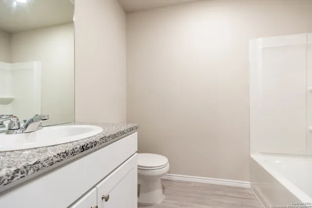 a bathroom with a granite countertop sink a toilet and a mirror