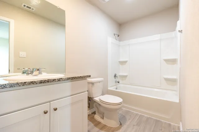 a bathroom with a granite countertop sink a toilet and shower
