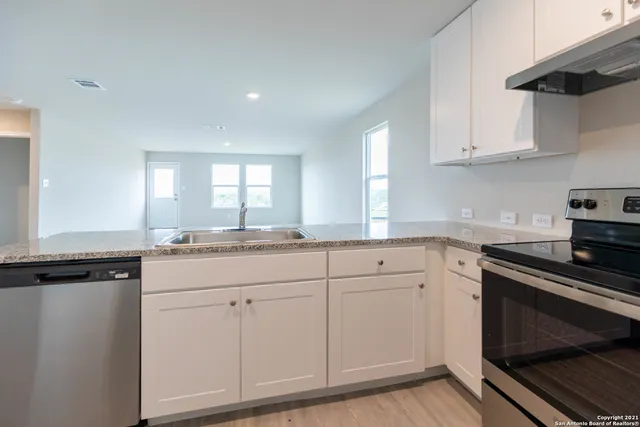 a kitchen with white cabinets and sink