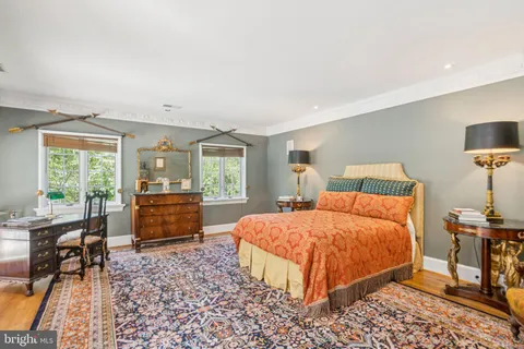 a bedroom with a bed table chair and a window