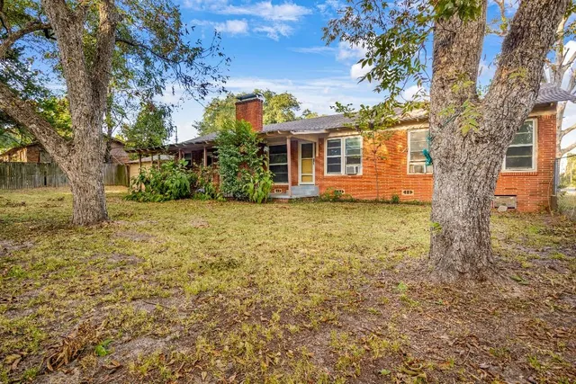 a view of a yard in front of a house with large trees