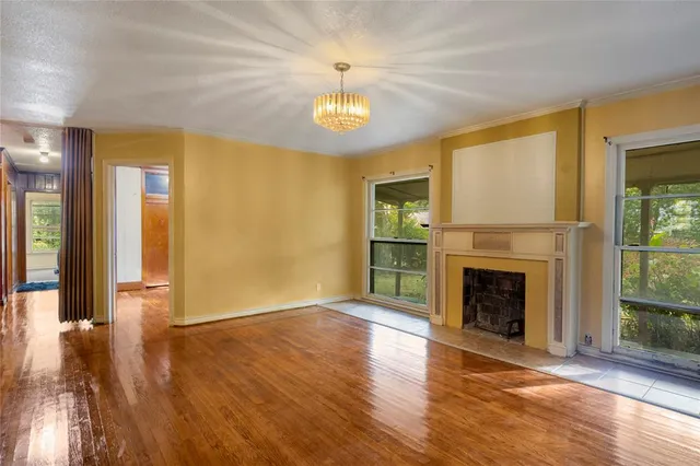a view of an empty room with window and wooden floor