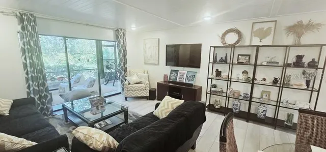 a living room with furniture a flat screen tv and a floor to ceiling window