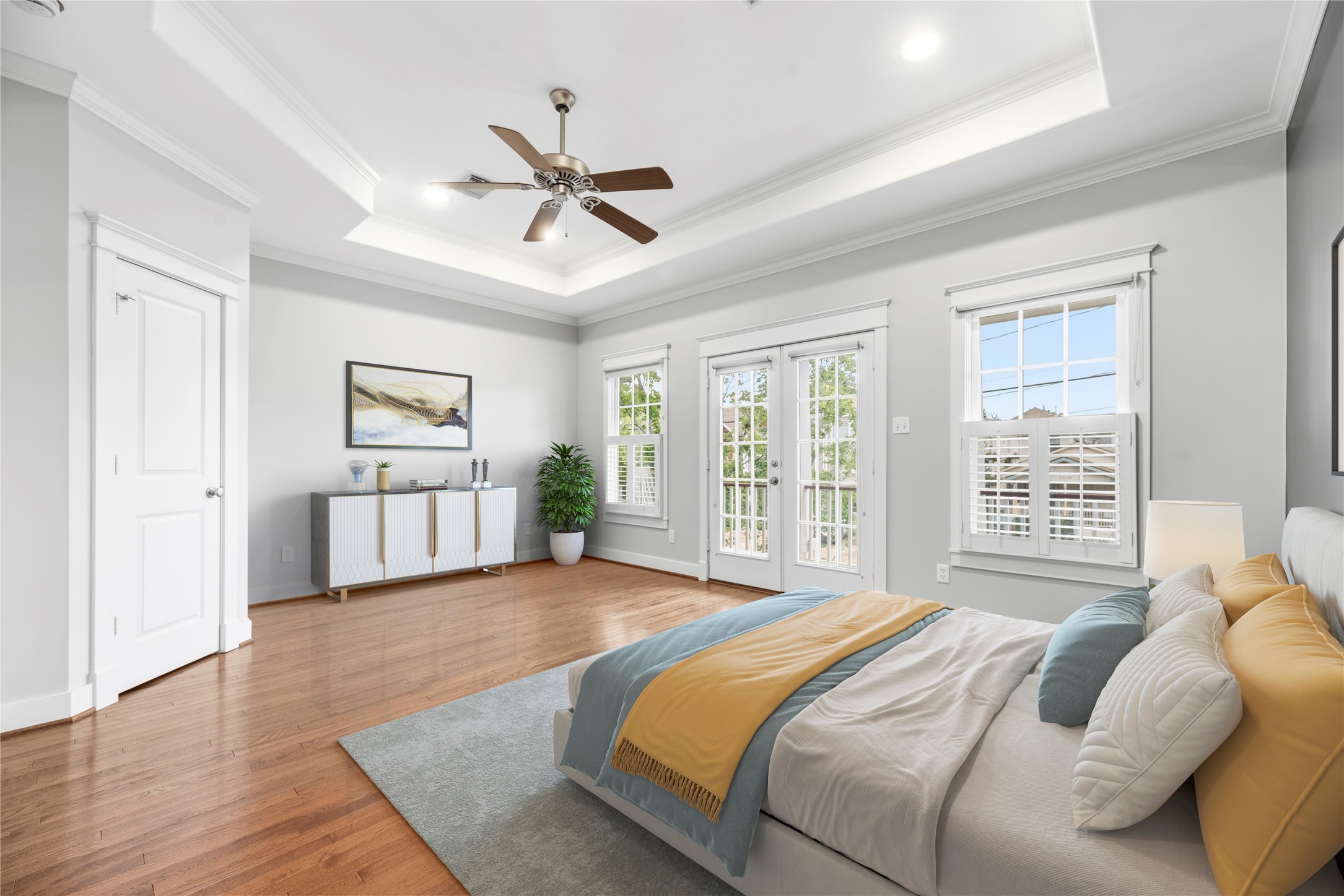 1505 Prince Street Houston, TX 77008 - Photo 18 of 39 Virtually staged view of the primary bedroom, featuring a tray ceiling, ceiling fan, accent wall, plantation shutters, and access to the upstairs balcony.
