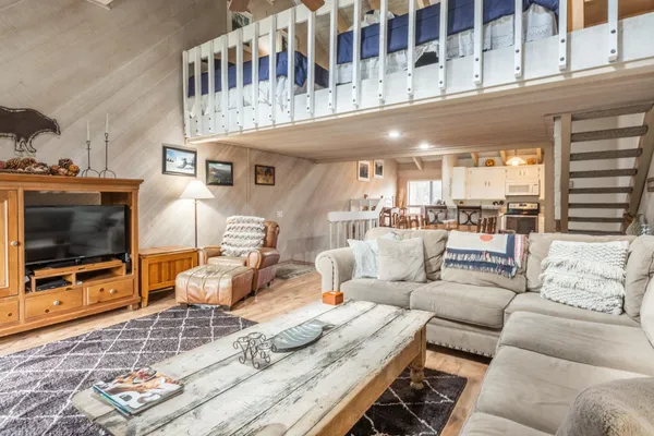 a living room with furniture a flat screen tv and a floor to ceiling window