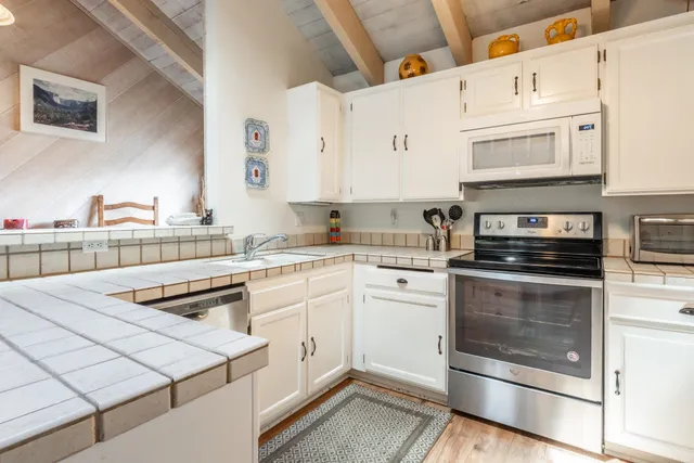 a kitchen with stainless steel appliances granite countertop a stove and white cabinets