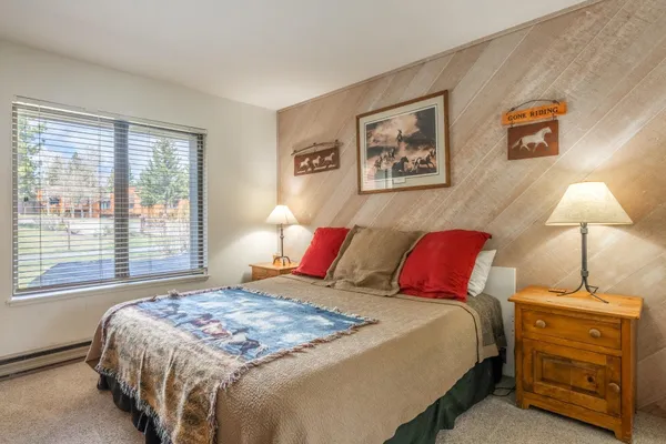 a bedroom with a bed and a lamp on dresser