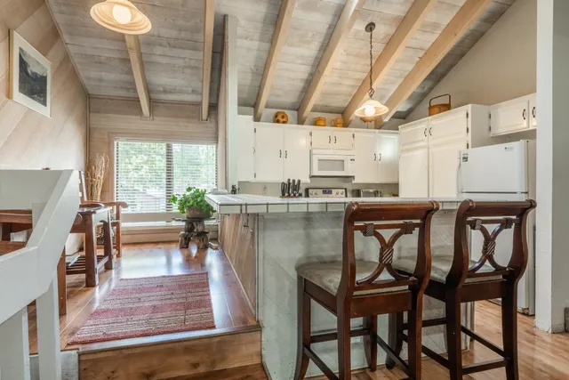 a kitchen with stainless steel appliances kitchen island granite countertop a table chairs sink and cabinets