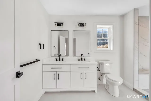 a bathroom with a double vanity sink a toilet and a mirror