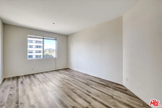 an empty room with wooden floor cabinet and windows