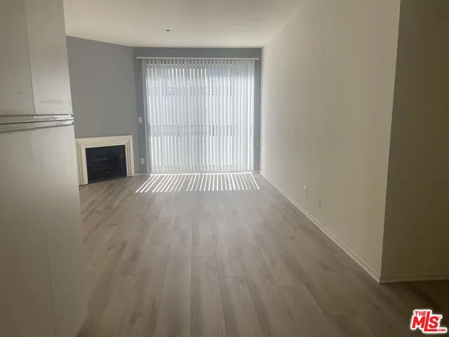 a view of empty room with wooden floor and fireplace