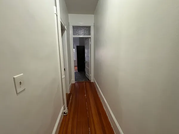 a view of a hallway with wooden floor and a ceiling fan