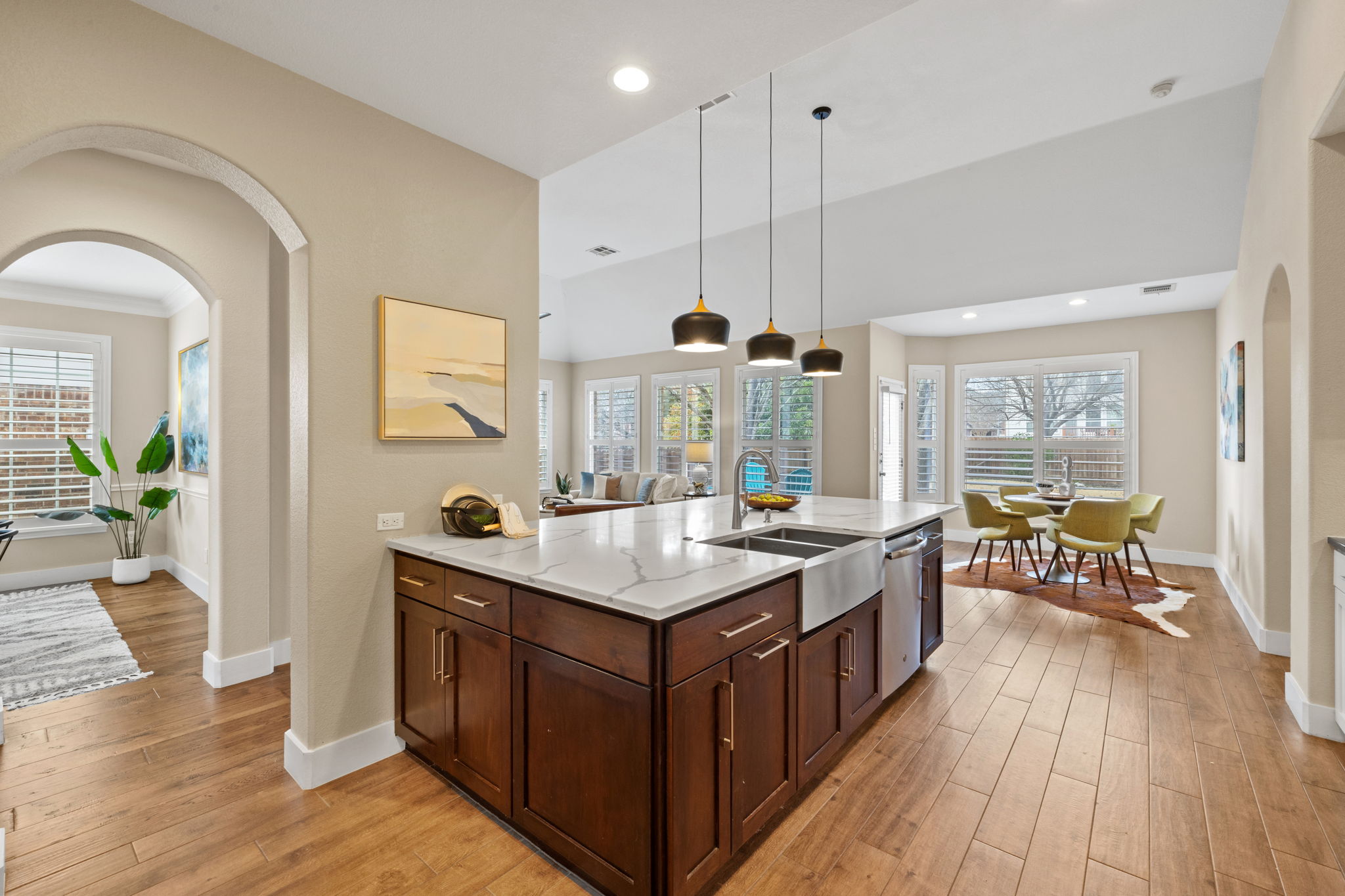 8112 Cobblestone Austin, TX 78735 - Photo 13 of 33 Kitchen with stainless steel dishwasher, light stone countertops, light wood-style flooring, arched walkways, and hanging light fixtures