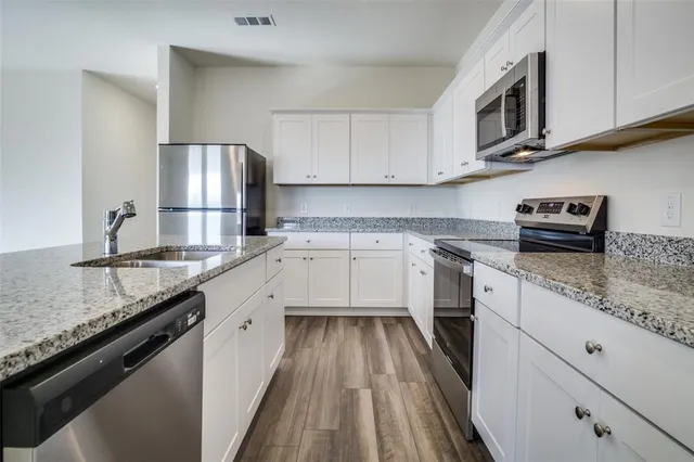 a kitchen with a refrigerator a stove top oven and wooden floor