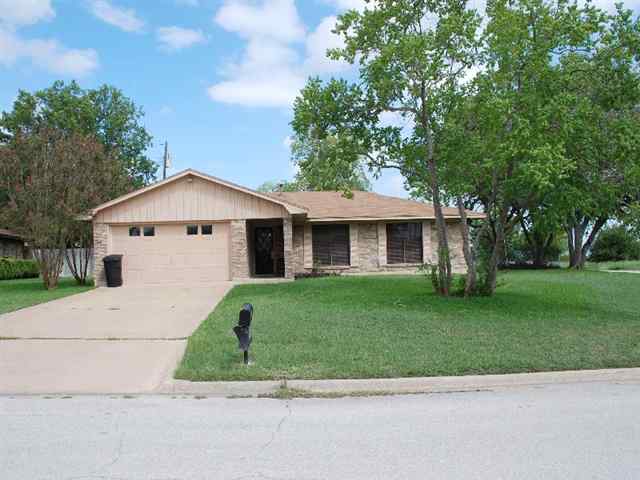 a view of a yard in front of a house with plants and large tree
