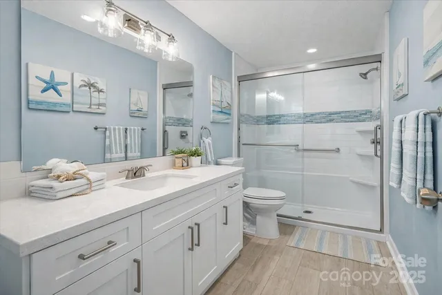 a bathroom with a granite countertop sink a toilet and shower