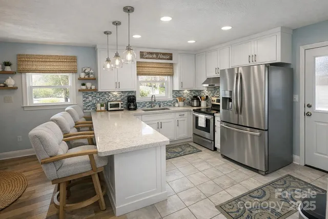 a kitchen with a refrigerator a stove a sink and chairs