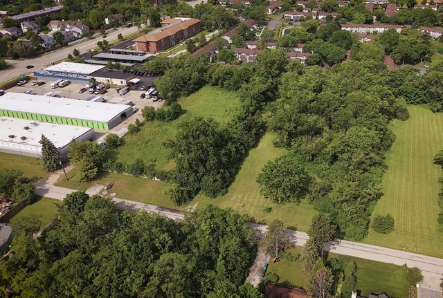 an aerial view of residential houses with outdoor space and trees all around