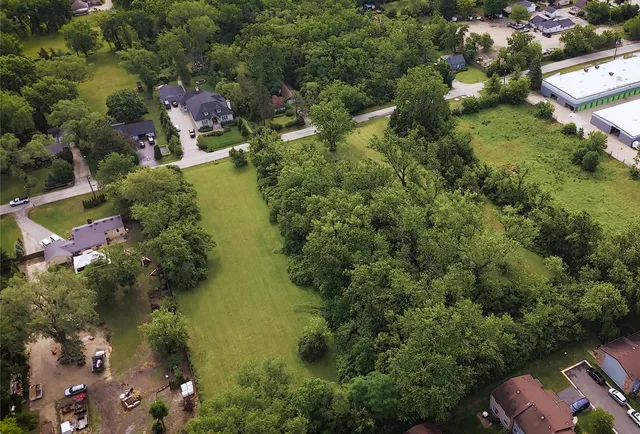 an aerial view of residential houses with outdoor space and trees