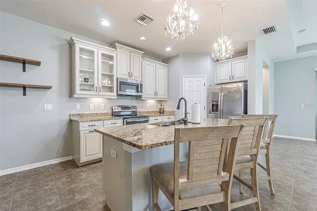 a kitchen with stainless steel appliances granite countertop a stove top oven a refrigerator a sink and a dining table with wooden floor