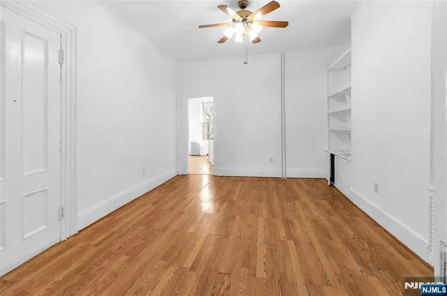 an empty room with wooden floor and fan