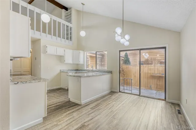 a kitchen with granite countertop a stove a sink and white cabinets with wooden floor