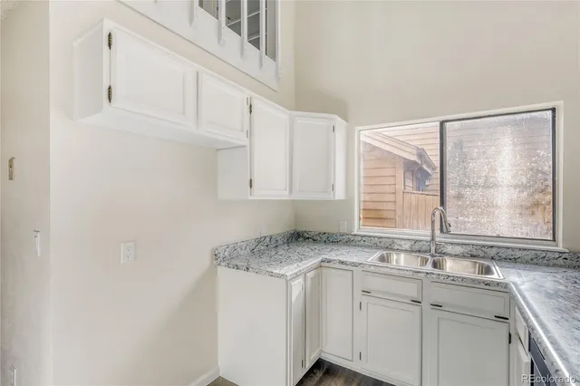 a kitchen with granite countertop a sink white cabinets and a window