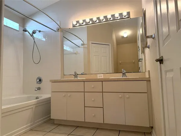 a bathroom with a double vanity sink a mirror and a bathtub