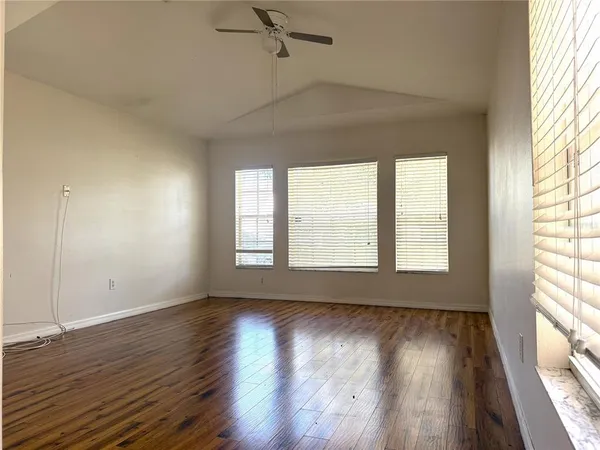 an empty room with wooden floor and windows