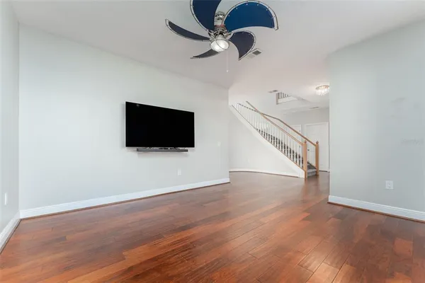 a view of empty room with wooden floor and fan
