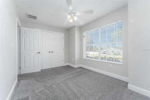 an empty room with windows and chandelier fan