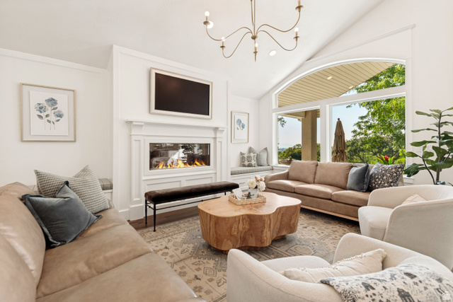 1567 Ridgeview Circle Farmington, UT 84025 - Photo 16 of 55 Vaulted ceiling with an elegant chandelier, a built-in linear fireplace with a detailed mantel, a window seat with storage, and large arched windows offering expansive outdoor views