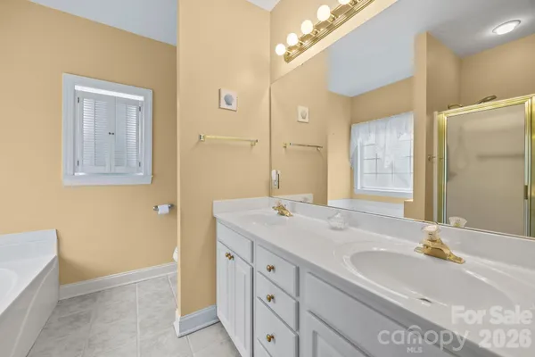 a bathroom with a sink double vanity granite tub shower and a mirror