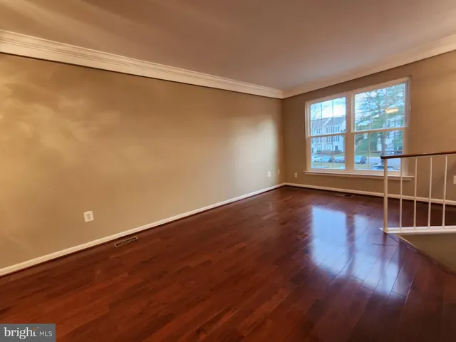 a view of an empty room with wooden floor and a ceiling fan