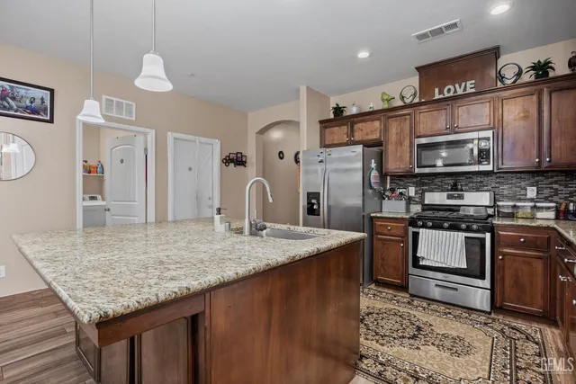 a kitchen with stainless steel appliances granite countertop a sink dishwasher stove and refrigerator