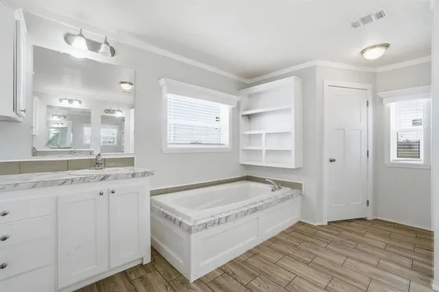 a spacious bathroom with a granite countertop sink and a bathtub