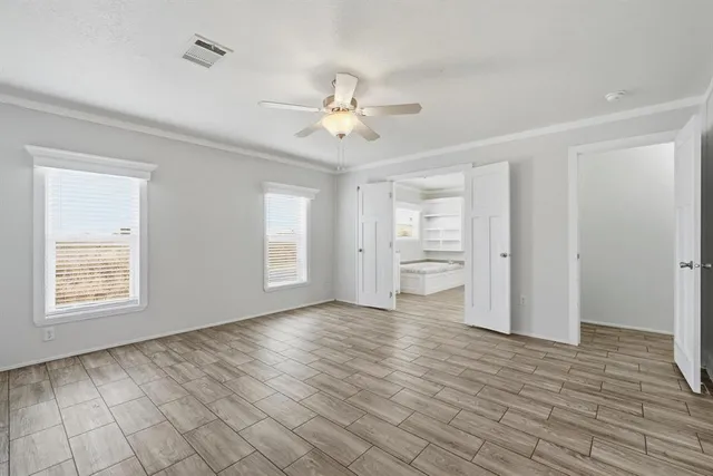 a view of an empty room with a window and wooden floor