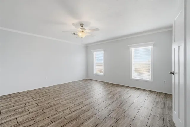 a view of an empty room with a window and wooden floor