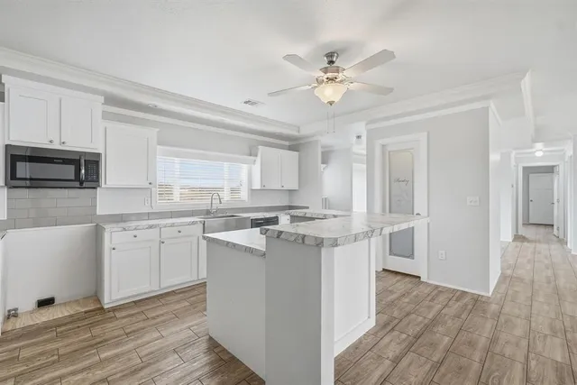 a kitchen with kitchen island granite countertop a sink cabinets and stainless steel appliances