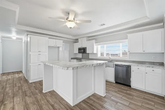 a kitchen with kitchen island granite countertop a sink cabinets and wooden floor