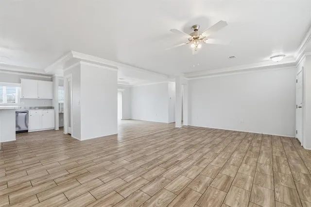 a view of an empty room with wooden floor and a ceiling fan