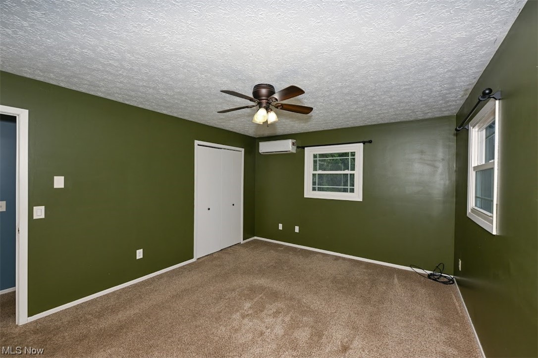 3368 Erhart Road Litchfield, OH 44253 - Photo 23 of 35 Empty room featuring carpet, ceiling fan, a wall mounted AC, and a textured ceiling