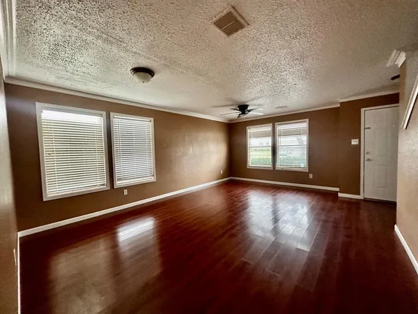 an empty room with wooden floor and windows