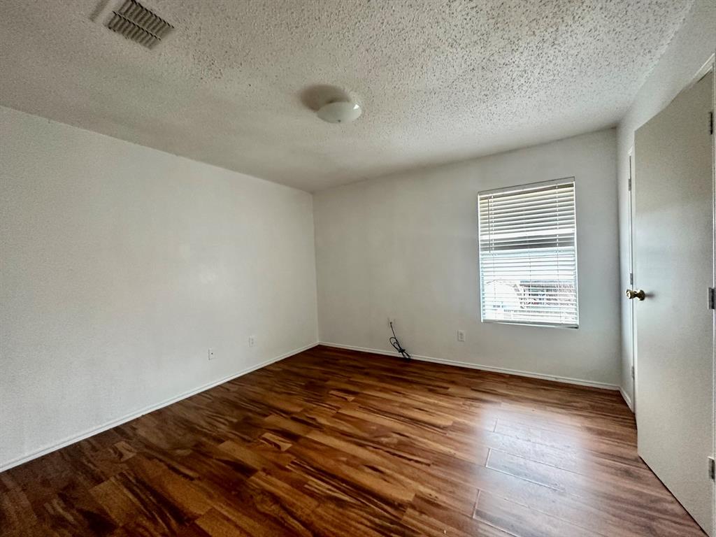 5437 New Castleton Lane Fort Worth, TX 76135 - Photo 7 of 16 an empty room with wooden floor and windows
